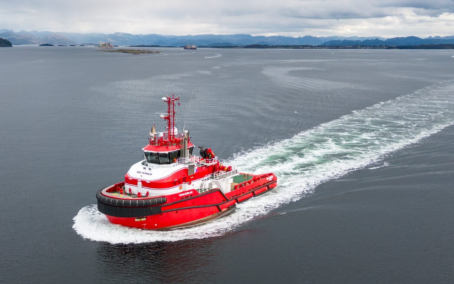 The red hybrid tug BB POWER underway in a Norwegian fjord