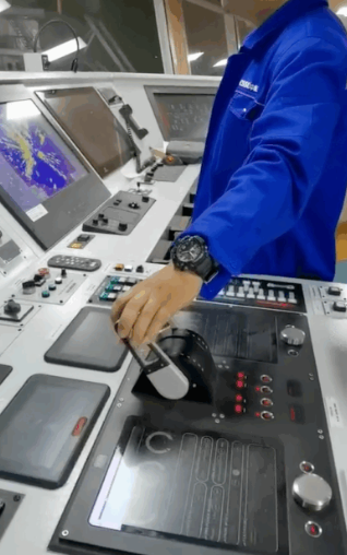 An operator using the propulsion control lever and display panel on a ship's bridge